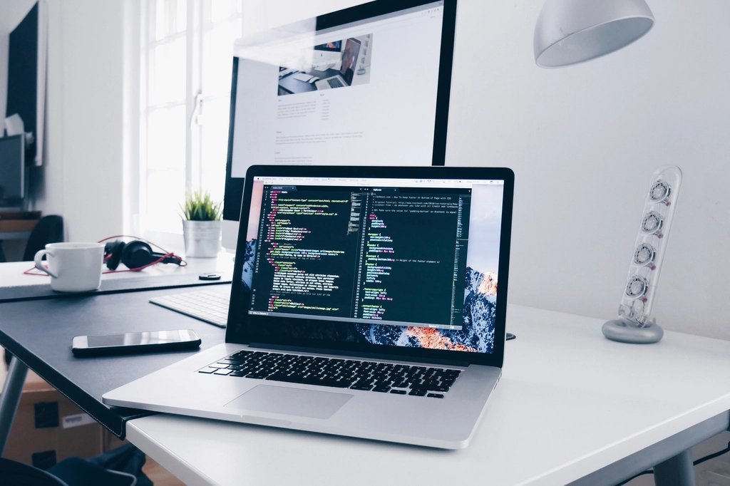 Laptop hiển thị mã nguồn website trên bàn làm việc